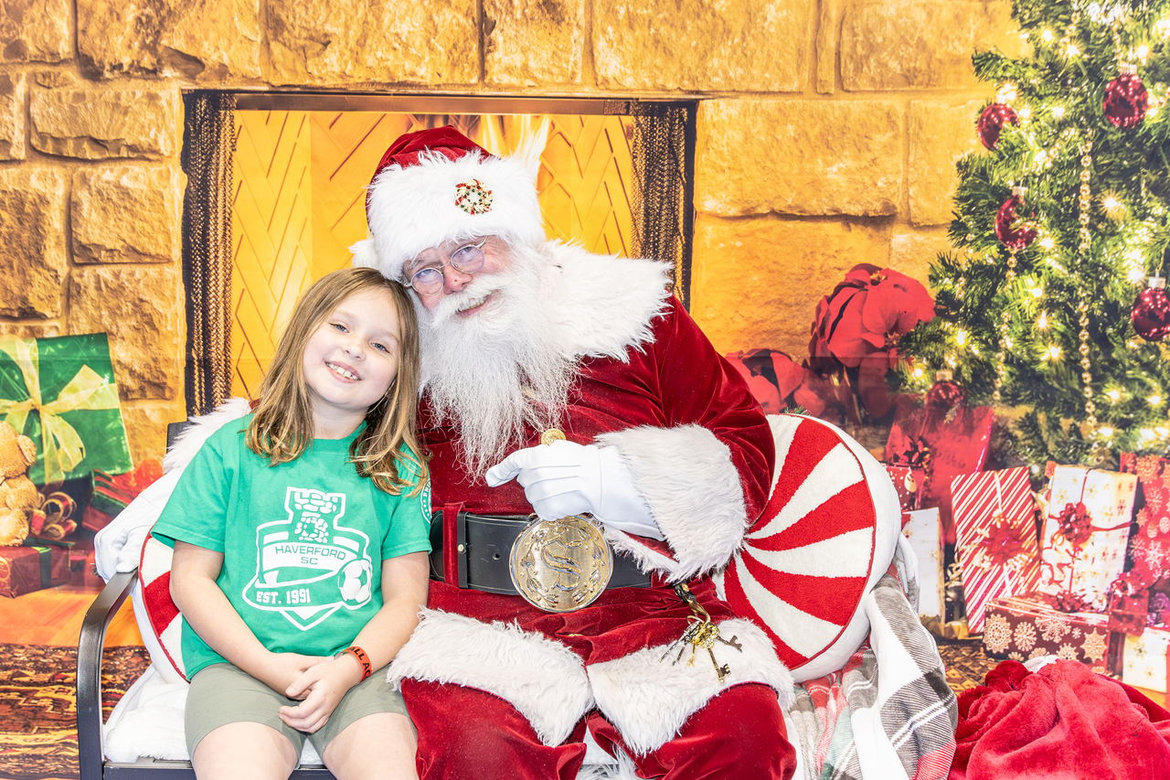 young girl sits with Santa for a photo at Skate with Santa at Marple Sports Arena