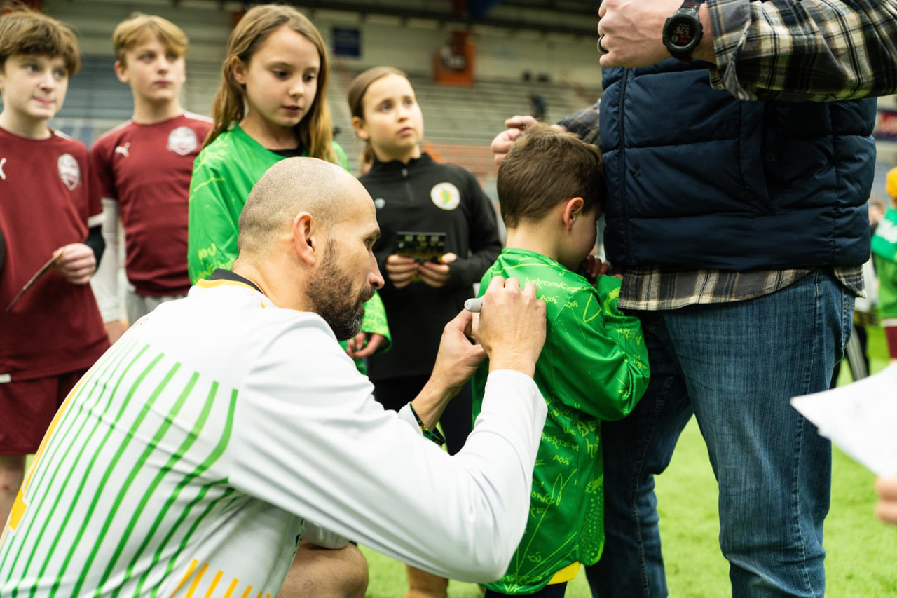 Team captain signing autograph on child's t-shirt