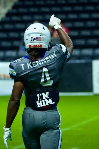 #4 Kennedy walks off confident after a big play, crowd roaring as teammates celebrate.