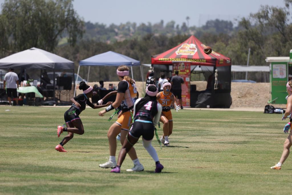 Girls flag football athletes closing in on a ball carrier