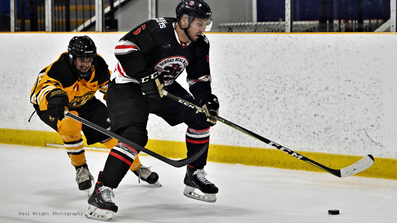 Paul Cianfrini (Dundas) with the puck being pestered by a Cambridge defender