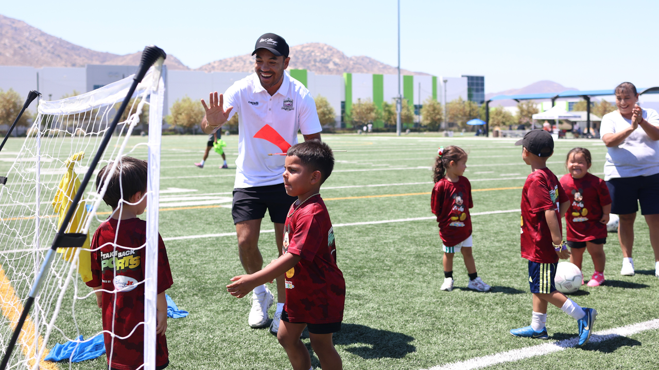 Photo of Marco Fabián looking to high five a camper during a training session